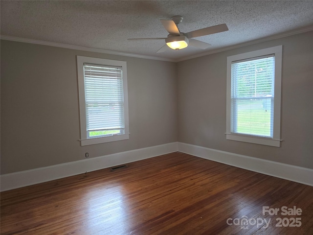 unfurnished room featuring plenty of natural light, a textured ceiling, wood finished floors, and visible vents