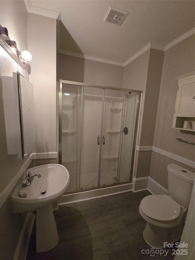 full bath featuring visible vents, ornamental molding, wood finished floors, toilet, and a stall shower