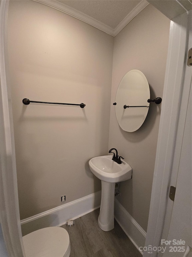 bathroom with crown molding, toilet, baseboards, and wood finished floors