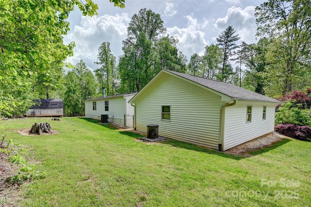 back of house featuring an outdoor structure, a storage shed, central AC, and a yard