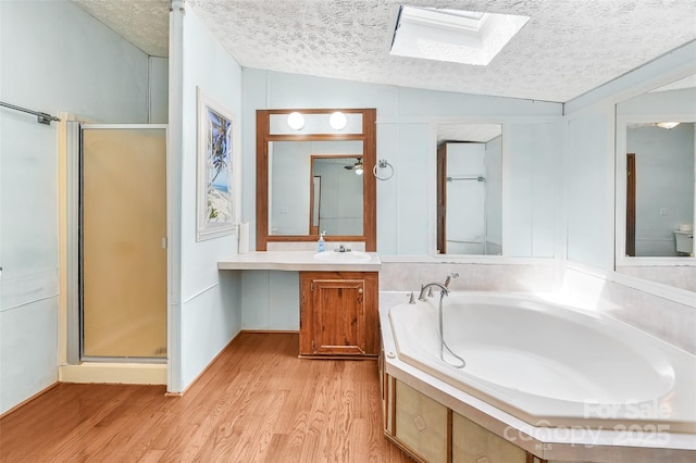 bathroom with wood finished floors, a textured ceiling, and a stall shower