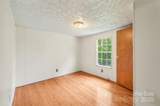 spare room featuring a textured ceiling and hardwood / wood-style flooring