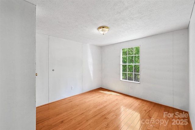 spare room with a textured ceiling and hardwood / wood-style floors