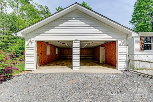 view of vehicle parking featuring a garage and fence