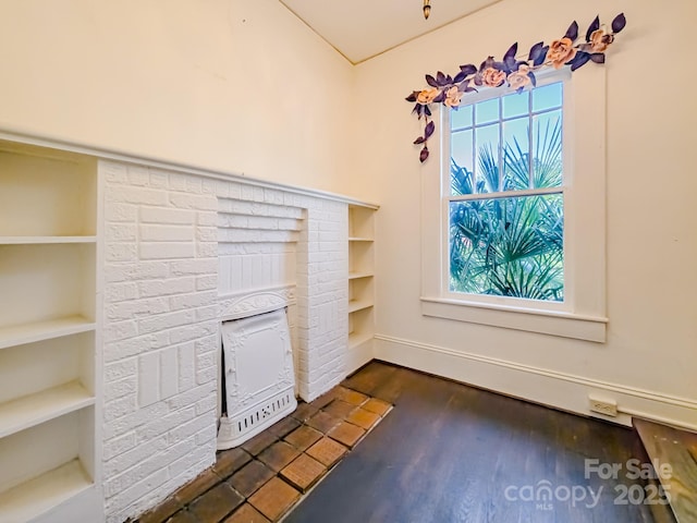 unfurnished living room featuring healthy amount of natural light, dark wood-style flooring, and built in features