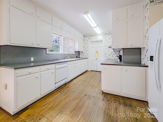 kitchen with white appliances, white cabinets, light wood-type flooring, and dark countertops