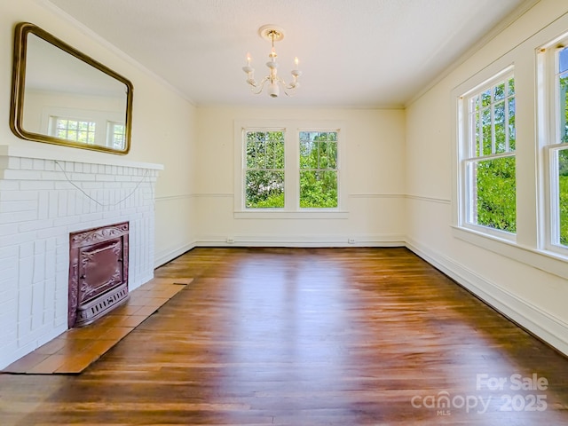 unfurnished living room featuring a chandelier, healthy amount of natural light, wood finished floors, and crown molding