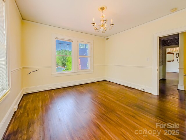 unfurnished room with a chandelier, wood finished floors, baseboards, and a smoke detector