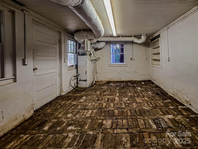 basement featuring brick flooring and heating unit