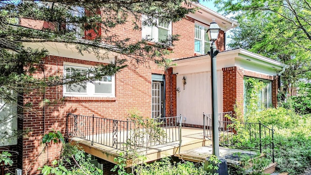 back of house with brick siding and a wooden deck