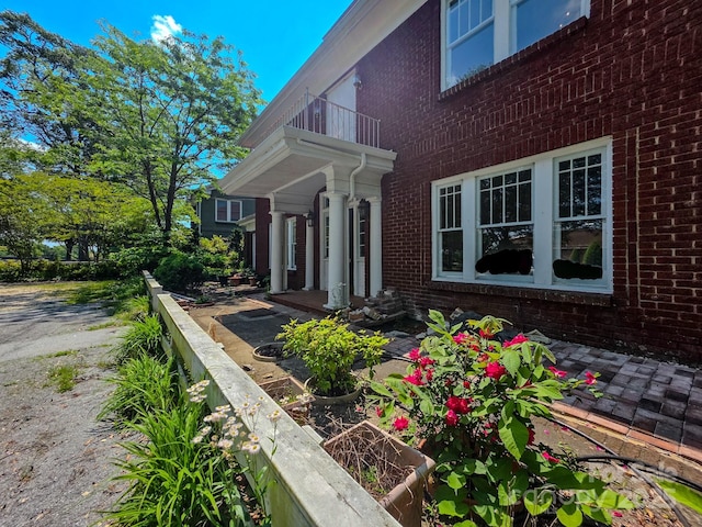 view of side of property with brick siding and a balcony