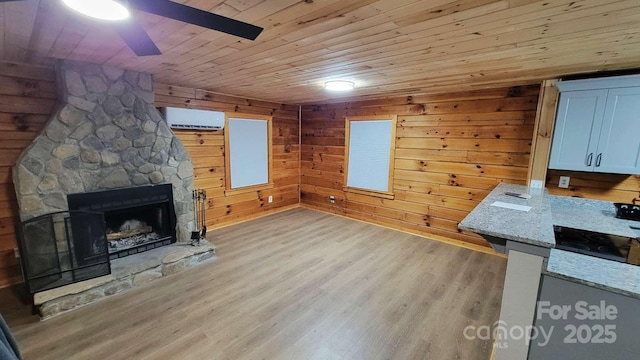 389 Lily Ln, Whittier, NC 28789 - unfurnished living room featuring wood ceiling, ceiling fan, a fireplace, a wall mounted AC, and light wood-type flooring