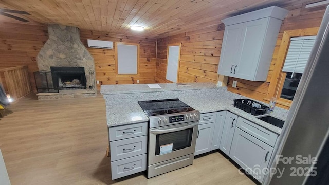 389 Lily Ln, Whittier, NC 28789 - kitchen with light wood-style floors, wood walls, a peninsula, and stainless steel range with electric stovetop