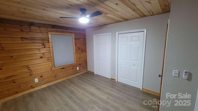 389 Lily Ln, Whittier, NC 28789 - unfurnished bedroom with wooden ceiling, baseboards, wood walls, and wood finished floors