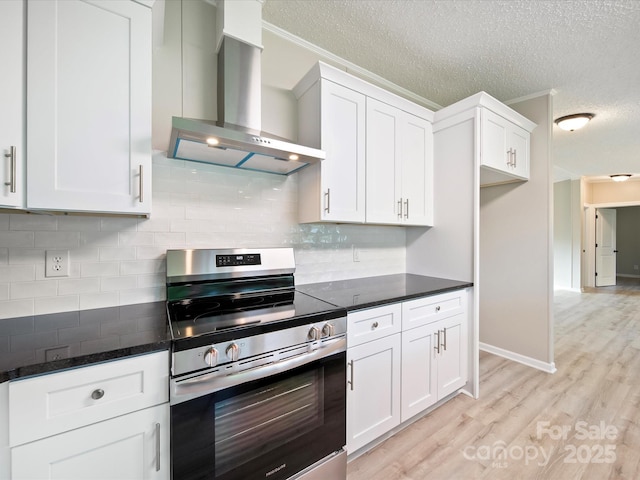 kitchen with stainless steel electric stove, wall chimney exhaust hood, white cabinetry, a textured ceiling, and light wood-style floors
