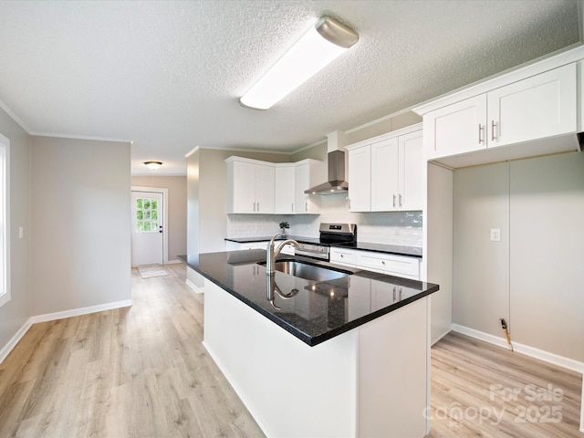 kitchen featuring wall chimney exhaust hood, a sink, light wood finished floors, stainless steel electric range, and white cabinetry