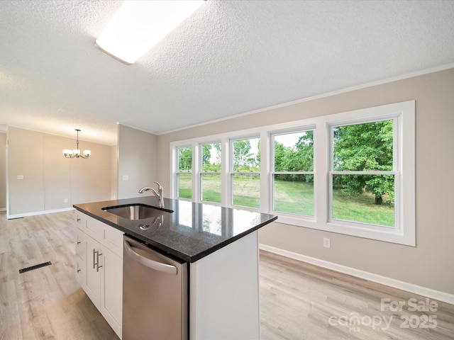 kitchen with a sink, dishwasher, light wood-type flooring, a textured ceiling, and healthy amount of natural light