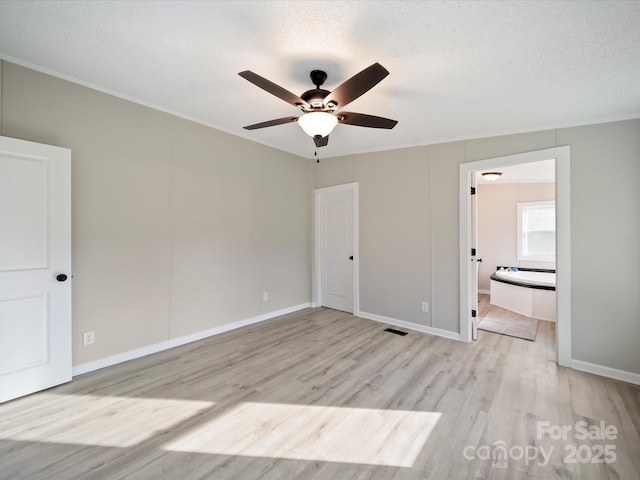 unfurnished bedroom featuring ornamental molding, light wood-style floors, ensuite bathroom, baseboards, and a ceiling fan