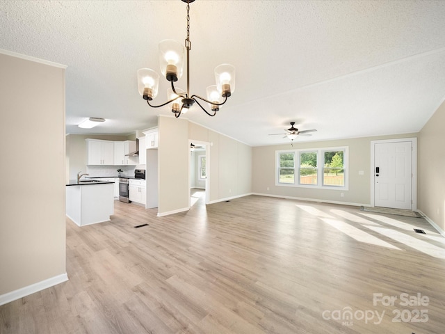 unfurnished living room with a ceiling fan, a chandelier, light wood finished floors, baseboards, and a textured ceiling