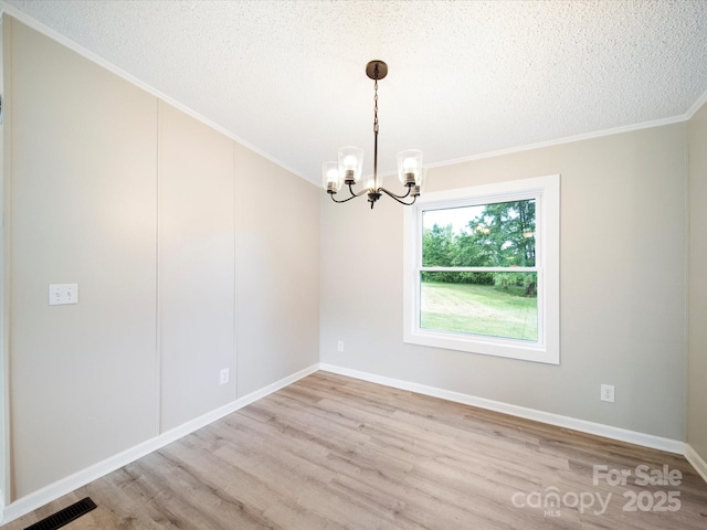 spare room featuring a chandelier, wood finished floors, crown molding, a textured ceiling, and baseboards