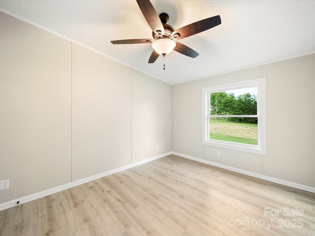 spare room with light wood-style flooring, a ceiling fan, ornamental molding, a textured ceiling, and baseboards