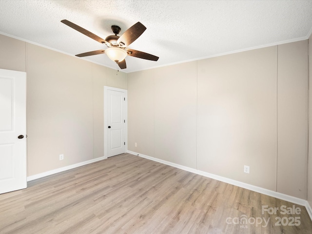 spare room featuring light wood finished floors, a ceiling fan, crown molding, a textured ceiling, and baseboards