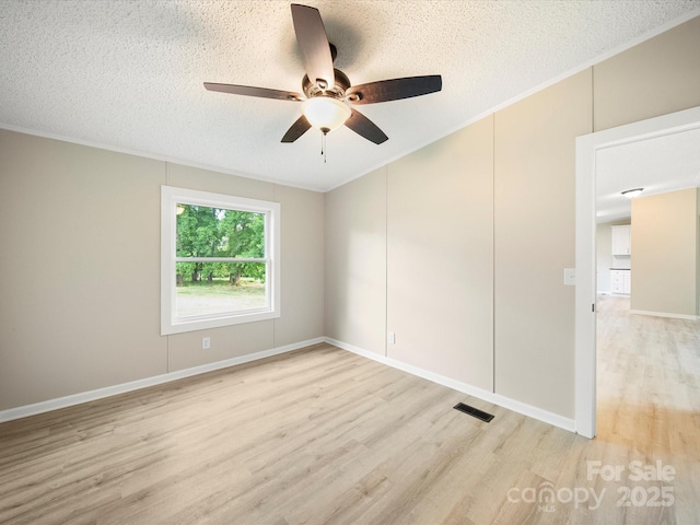 empty room featuring a ceiling fan, light wood-style floors, a textured ceiling, and ornamental molding