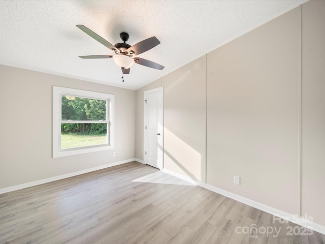 unfurnished room featuring light wood finished floors, a ceiling fan, a textured ceiling, and baseboards