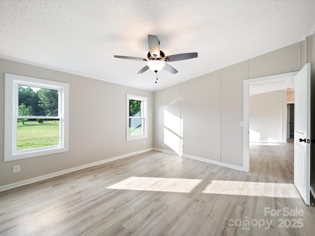 unfurnished bedroom with a textured ceiling, light wood finished floors, baseboards, and ceiling fan