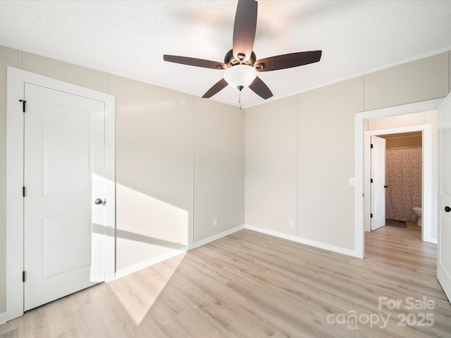 unfurnished bedroom featuring light wood-style floors, a textured ceiling, ornamental molding, a ceiling fan, and baseboards