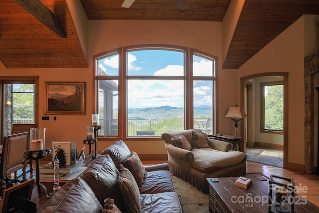 living area featuring vaulted ceiling, wood ceiling, a ceiling fan, and a mountain view