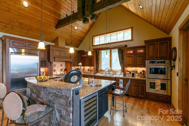 kitchen with beverage cooler, appliances with stainless steel finishes, a kitchen bar, and a sink