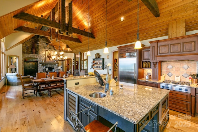 kitchen featuring built in appliances, a center island with sink, a sink, and light wood-style floors