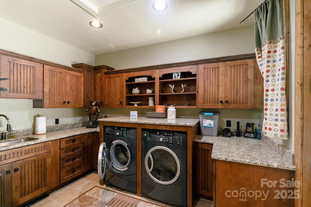 washroom with washing machine and clothes dryer, cabinet space, light tile patterned flooring, and a sink