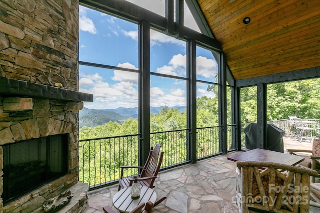 sunroom with a wealth of natural light, an outdoor stone fireplace, and a mountain view