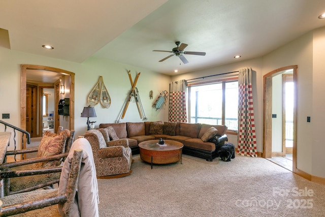carpeted living room with ceiling fan, arched walkways, and recessed lighting