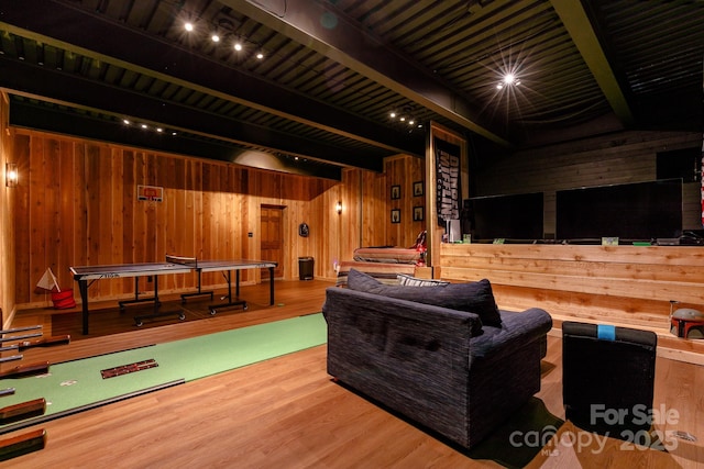 playroom with wooden walls, beamed ceiling, and wood finished floors