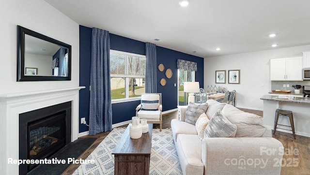 living area featuring recessed lighting, dark wood-style floors, baseboards, and a fireplace