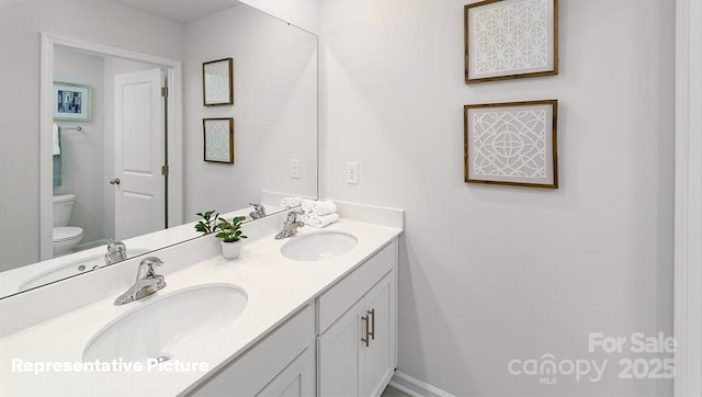 bathroom featuring toilet and double vanity