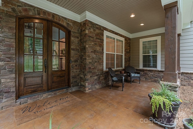 entrance to property featuring covered porch, french doors, and stone siding