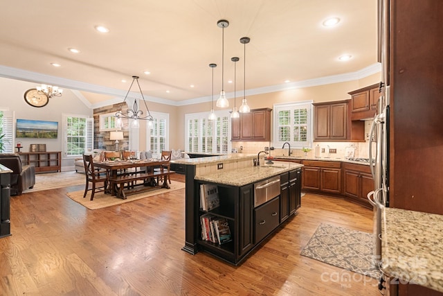 kitchen featuring open floor plan, a center island with sink, a chandelier, tasteful backsplash, and a warming drawer