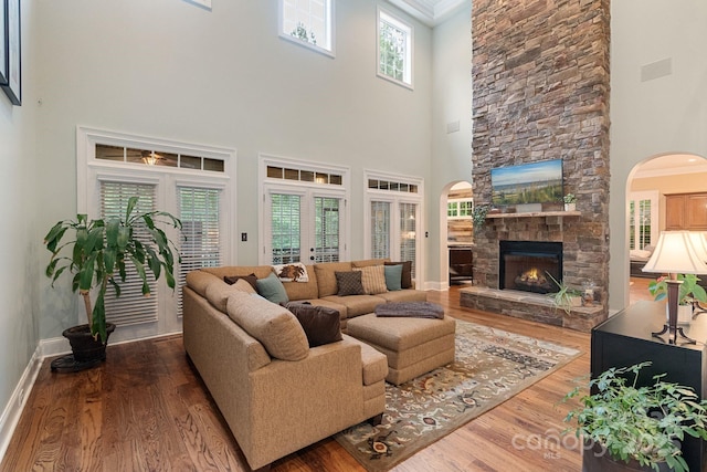living area featuring wood finished floors, arched walkways, and a high ceiling