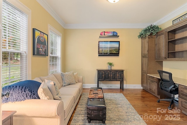 living area with crown molding, built in desk, wood finished floors, and a wealth of natural light