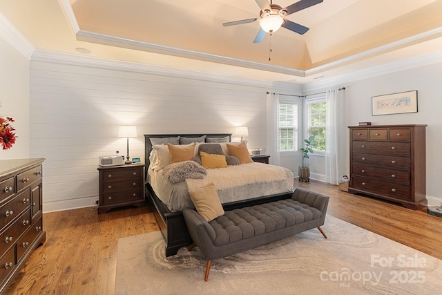 bedroom with ornamental molding, a raised ceiling, ceiling fan, and wood finished floors