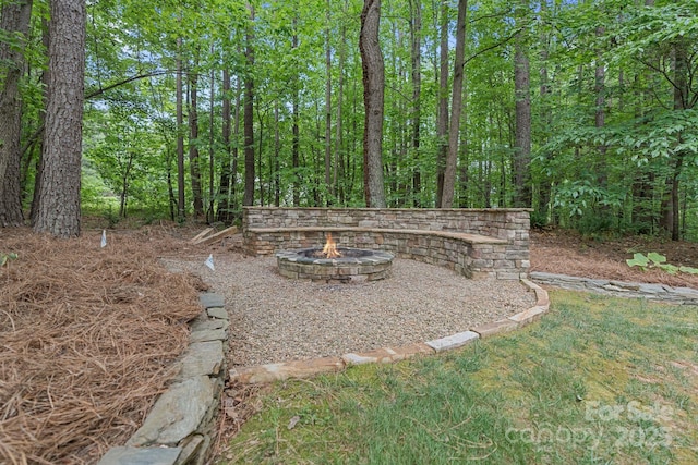 view of yard with a view of trees and a fire pit