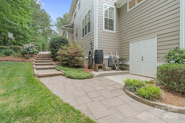 entrance to property featuring a lawn and a patio area