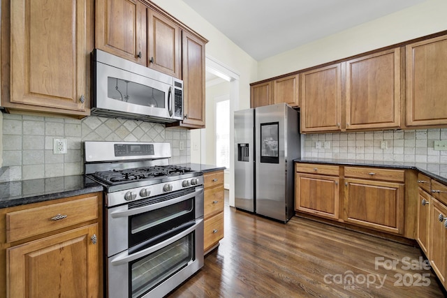 1855 Second Baxter Xing, Fort Mill, SC 29708 - kitchen featuring stainless steel appliances, tasteful backsplash, dark wood-style flooring, dark stone countertops, and brown cabinetry