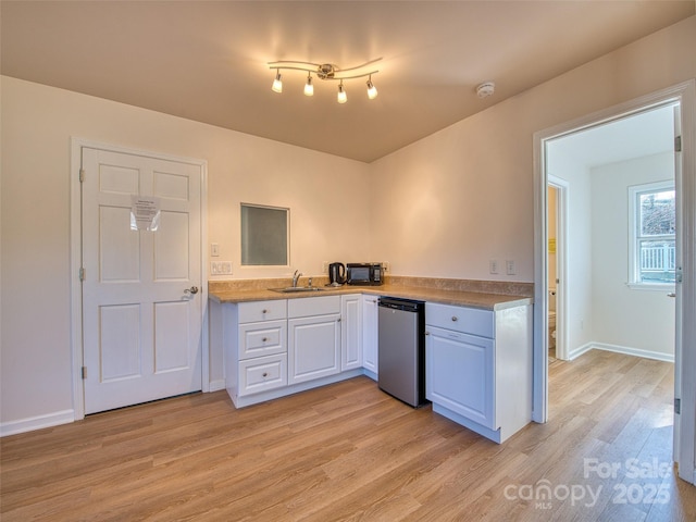 kitchen featuring light wood finished floors, a sink, white cabinetry, baseboards, and dishwasher
