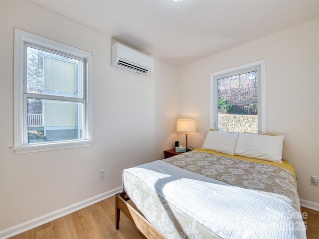 bedroom featuring baseboards, a wall unit AC, and wood finished floors
