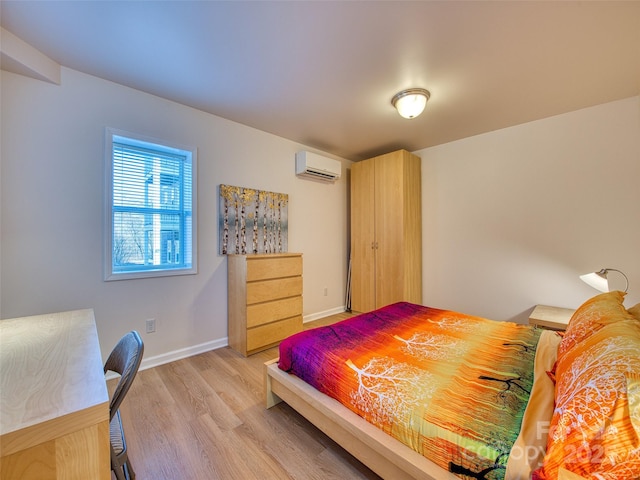 bedroom with a wall mounted AC, baseboards, and light wood-type flooring